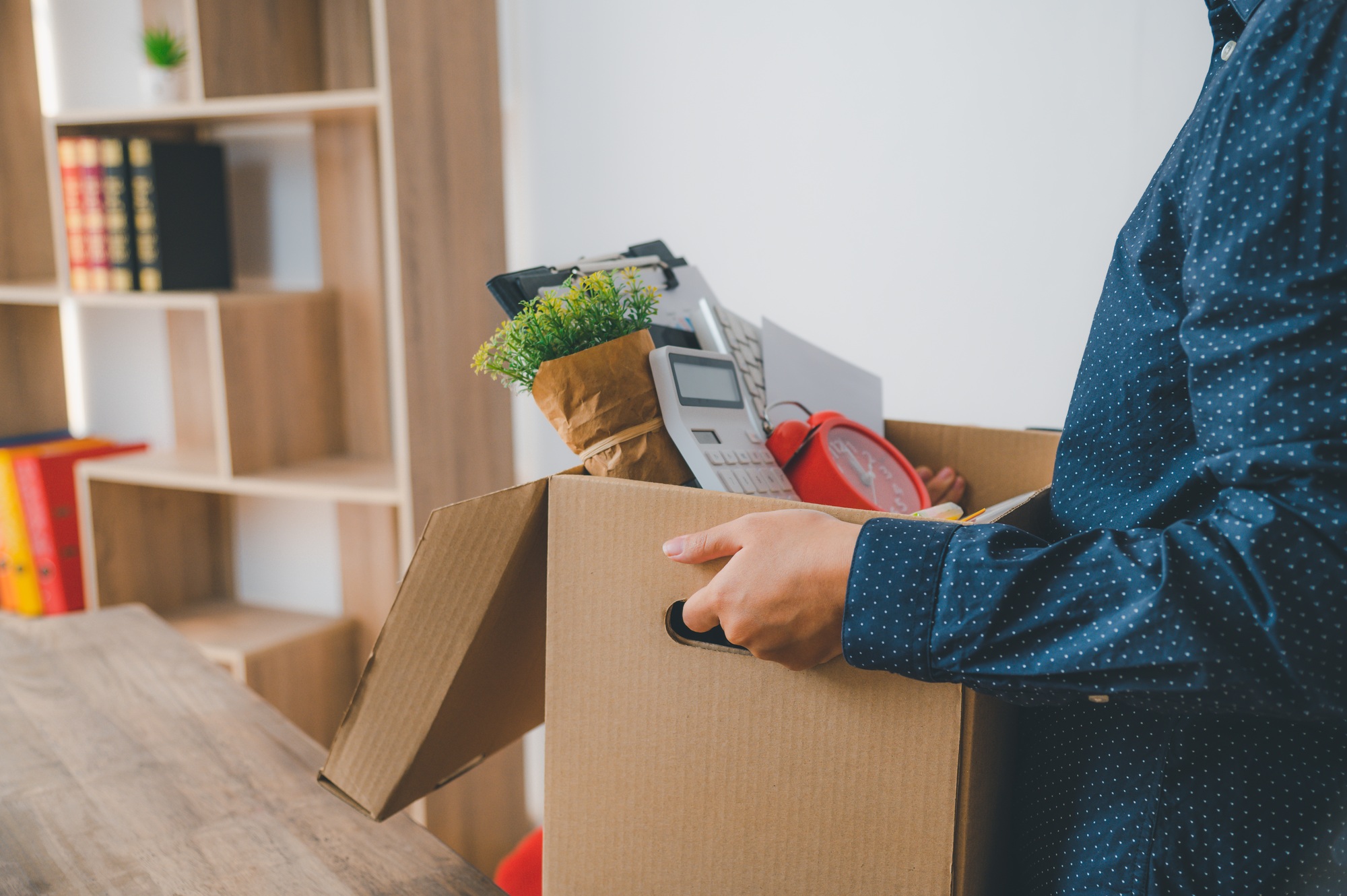 Female firm employee leaving the office with cardboard boxes containing office supplies